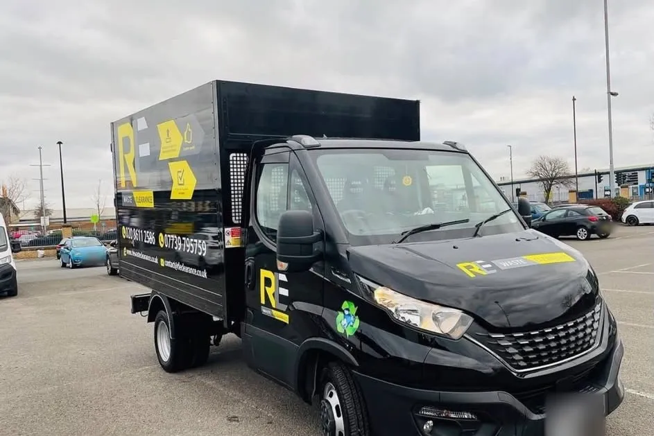 RLE Waste Clearance black tipper truck with a high cage and yellow livery, parked in a car park