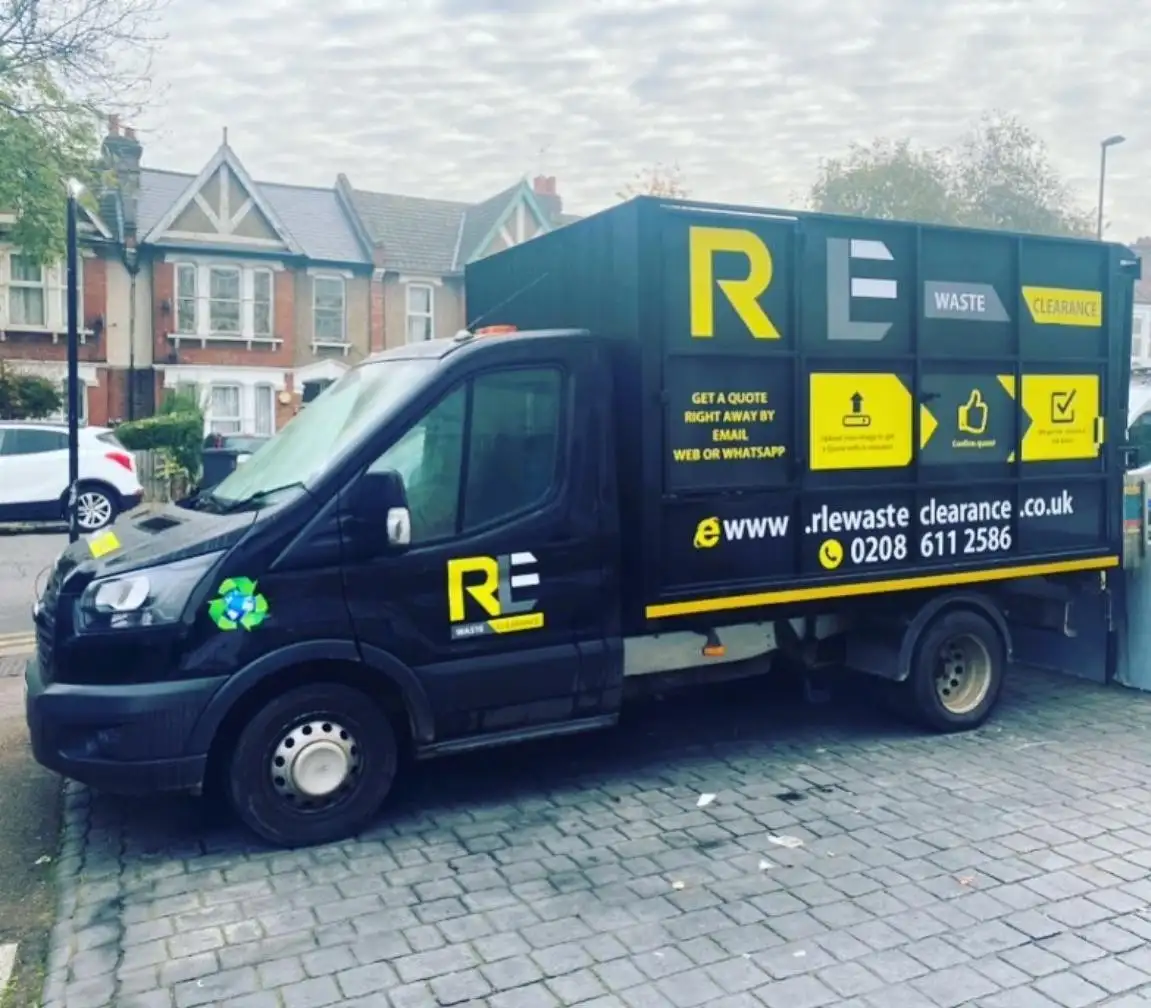 RLE Waste Clearance truck in black and yellow livery parked on block paving in front of a row of terraced houses