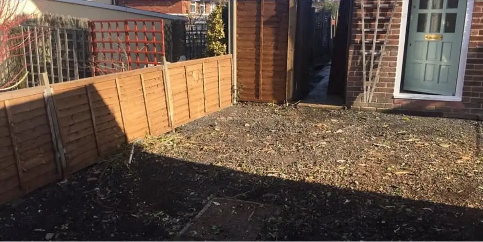 After: The front garden cleared to bare earth in front of a new wooden fence