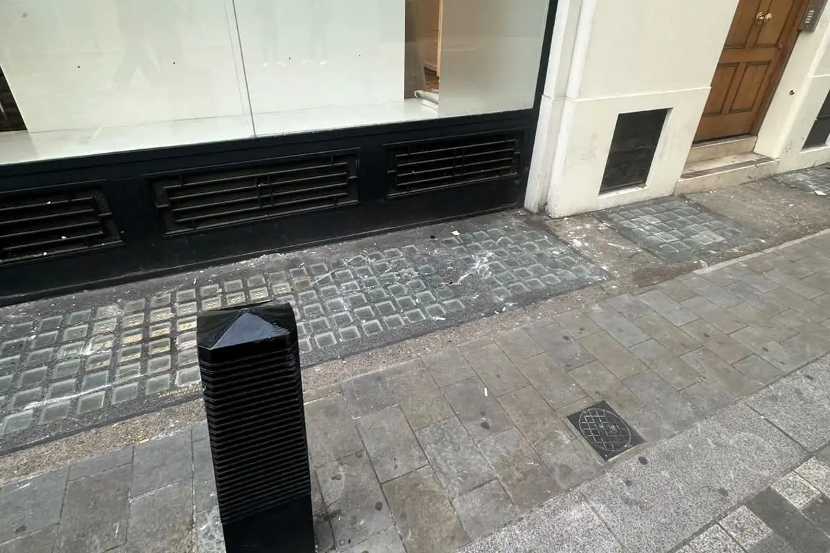 After: The pavement in front of the shop window cleared, beside a black bollard